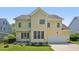 Rear exterior showcasing a two-story yellow home with a two-car garage and manicured lawn at 1104 Dominion Hill Dr, Cary, NC 27519