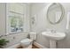 Bright powder room features a pedestal sink, round mirror, and a window with blinds for natural light at 1104 Dominion Hill Dr, Cary, NC 27519