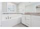 Bright bathroom features a soaking tub with decorative tile and granite countertop vanity at 114 Cross Country Way, Durham, NC 27703