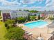 Aerial view of community pool with lounge chairs and umbrellas by colorful townhomes at 114 Cross Country Way, Durham, NC 27703