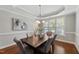 Bright dining room with dark wood table, six upholstered chairs, wainscoting, and tray ceiling at 117 Woodlark Ln, Holly Springs, NC 27540