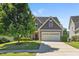 Charming home featuring a manicured lawn, two car garage, and stone and gray shingle exterior at 117 Woodlark Ln, Holly Springs, NC 27540