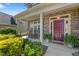 Inviting front porch with stone accents, rocking chairs, lush plants, and a vibrant maroon front door at 117 Woodlark Ln, Holly Springs, NC 27540