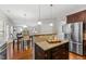 Open kitchen with granite countertops, stainless steel appliances, wooden floors, and views into the living room at 117 Woodlark Ln, Holly Springs, NC 27540