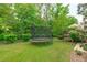 Well-maintained backyard featuring a trampoline, lush green lawn, and mature trees at 1401 Everette Fields Rd, Morrisville, NC 27560