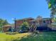 Backyard with a brick two-story home, mature trees, wooden stairs, and a lawn at 1509 Logan St, Durham, NC 27704