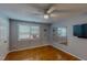 Neutral bedroom featuring hardwood floors, ceiling fan, and natural light, plus a wall-mounted television at 1509 Logan St, Durham, NC 27704