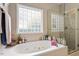 A luxurious bathroom features a large soaking tub, glass block window, and a separate glass-enclosed shower at 151 Donnibrook, Fuquay Varina, NC 27526