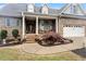 Inviting front porch with rocking chairs, brick pillars, hanging plants, and manicured landscaping at 151 Donnibrook, Fuquay Varina, NC 27526