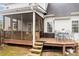 Cozy screened porch with wood floors and railings, adjacent to a deck with outdoor seating and a small table at 151 Donnibrook, Fuquay Varina, NC 27526