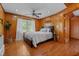 Comfortable bedroom featuring wood paneling, hardwood floors, ceiling fan, and natural light at 1661 Reno Sharps Store Rd, Bear Creek, NC 27207