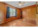Spacious bedroom featuring wood paneling, hardwood floors, ceiling fan, and bright windows at 1661 Reno Sharps Store Rd, Bear Creek, NC 27207