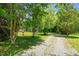Gravel driveway leading through mature trees, offering a charming approach to the welcoming country property at 1661 Reno Sharps Store Rd, Bear Creek, NC 27207