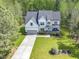 An aerial view shows a beautiful home with a long driveway surrounded by mature trees and a landscaped front yard at 1723 River Club Way, Franklinton, NC 27525