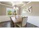 The dining room features a large window, modern light fixture, and elegant white wainscoting details at 1723 River Club Way, Franklinton, NC 27525