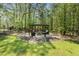 Relaxing backyard pergola with stone flooring, seating, and lush greenery, surrounded by towering trees at 1723 River Club Way, Franklinton, NC 27525