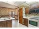 Eat-in kitchen features wood cabinets, white appliances, and unique floral wallpaper at 1725 Briarforest Pl, Raleigh, NC 27615