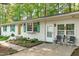 Side exterior view featuring a white brick facade, green shutters, a small patio, and landscaping at 1805 Holly St, Apex, NC 27502