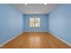 Empty bedroom featuring light blue walls, hardwood floors, and a bright window at 2037 Gurney Ct, Burlington, NC 27215