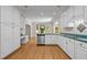 Well-lit kitchen with white cabinets and stainless steel appliances open to adjoining room at 2037 Gurney Ct, Burlington, NC 27215