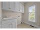 Functional laundry room with sink, white cabinets, and window for natural light at 2037 Gurney Ct, Burlington, NC 27215