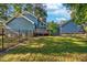 Expansive backyard featuring lush green grass, mature trees, and a charming swing set at 206 Cottrell Dr, Louisburg, NC 27549