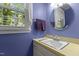 Charming bathroom with purple walls, round mirror, and natural light from the window at 2113 Port Royal Rd, Raleigh, NC 27609