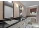 Traditional bathroom featuring double sinks, mirrors, a black countertop, and textured wallpaper at 2113 Port Royal Rd, Raleigh, NC 27609