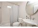 Well-lit bathroom with a pedestal sink, tiled walls, and a shower with a striped curtain at 2210 Milburnie Rd, Raleigh, NC 27610