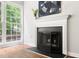 Cozy fireplace with mantle and large windows showcasing the outdoor view at 2301 Bolingbrook Ln, Raleigh, NC 27613