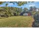 Large backyard featuring lush greenery, mature trees, and a storage shed at 251 Charles Riddle Rd, Sanford, NC 27330