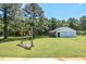 Lush backyard featuring a well-maintained lawn, mature trees, and a detached two-car garage at 2717 Jack Rd, Clayton, NC 27520