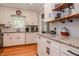 Bright kitchen featuring white cabinets, granite countertops, hardwood floors and convenient open shelving and modern appliances at 2717 Jack Rd, Clayton, NC 27520