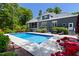 Backyard swimming pool with patio, beautiful landscaping, and a dark colored house at 30 Ocoee Falls Dr, Chapel Hill, NC 27517