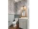Charming powder room with stylish wallpaper, wainscoting, and a wooden-framed mirror at 30 Ocoee Falls Dr, Chapel Hill, NC 27517
