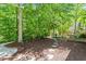 A tranquil backyard featuring mulch, stepping stones, mature trees, and a glimpse of a charming outbuilding at 300 Livingstone Dr, Cary, NC 27513