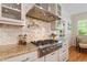 The gourmet kitchen features a stainless steel range hood, granite countertops, and subway tile backsplash at 300 Livingstone Dr, Cary, NC 27513