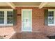 Close-up of a brick home entrance featuring a light blue door, symmetrical windows, and a decorative brick floor at 305 E Holmes St, Benson, NC 27504