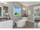 A luxurious bathroom featuring an oval soaking tub, dual vanities, and a large window at 318 Ivy Ridge Rd, Chapel Hill, NC 27516