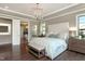 A luxurious bedroom with hardwood floors, bench, chandelier, and a view into the bathroom at 318 Ivy Ridge Rd, Chapel Hill, NC 27516