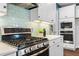 A modern kitchen featuring stainless steel appliances, white cabinets, an aqua backsplash, and hardwood floors at 3678 Horton Hill Dr, New Hill, NC 27562