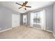 This bright bedroom has neutral carpeting, two windows with sheer curtains, and a ceiling fan at 3945 Amelia Park Dr, Raleigh, NC 27606