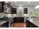 Well-equipped kitchen featuring stainless steel appliances, granite countertops, and dark wood cabinets at 4 Seawell Ct, Durham, NC 27703