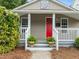 Cozy front porch with a bright red door, white railing and steps, and lush potted plants at 401 Haywood St, Raleigh, NC 27601