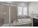 Bathroom featuring a soaking tub, glass shower, tile flooring, and a large window at 43 Quarter Gate Trce, Chapel Hill, NC 27516