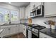 Close up view of a modern kitchen with a stainless steel oven and microwave and a black countertop at 43 Quarter Gate Trce, Chapel Hill, NC 27516
