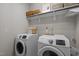 A laundry room with front loading Samsung washer and dryer units, shelving and decor at 43 Quarter Gate Trce, Chapel Hill, NC 27516