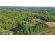 A beautiful aerial view of a single Gathering home next to a pond, surrounded by lush greenery and nature at 5250 Sartin Rd, Burlington, NC 27217