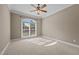 A bedroom with a ceiling fan, neutral-colored carpet, and a large window that allows for plenty of natural light at 5250 Sartin Rd, Burlington, NC 27217