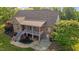 Aerial view showcasing the brick home's rear facade, complete with a covered patio and lush surroundings at 5250 Sartin Rd, Burlington, NC 27217